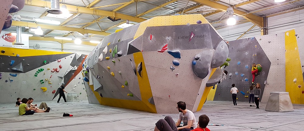 La salle de bloc et ses gros volumes, grimpeurs sur les murs et sur les tapis · Photo Planet Grimpe